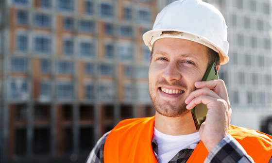 A construction foreman speaks by phone with a customer.