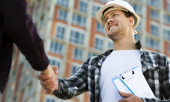 A construction foreman shakes hands with a customer.