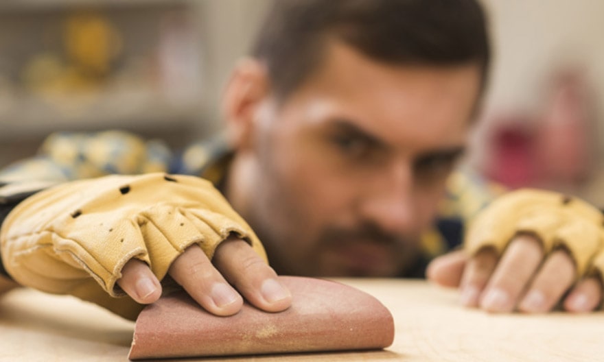 A home remodeling craftsman carefully sands a wooden part.