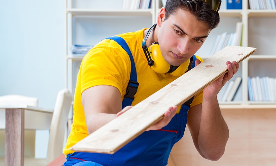 A contractor carefully examines a board