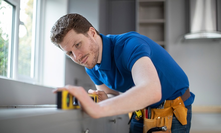 A contractor carefully checks the level of a new window sill. 