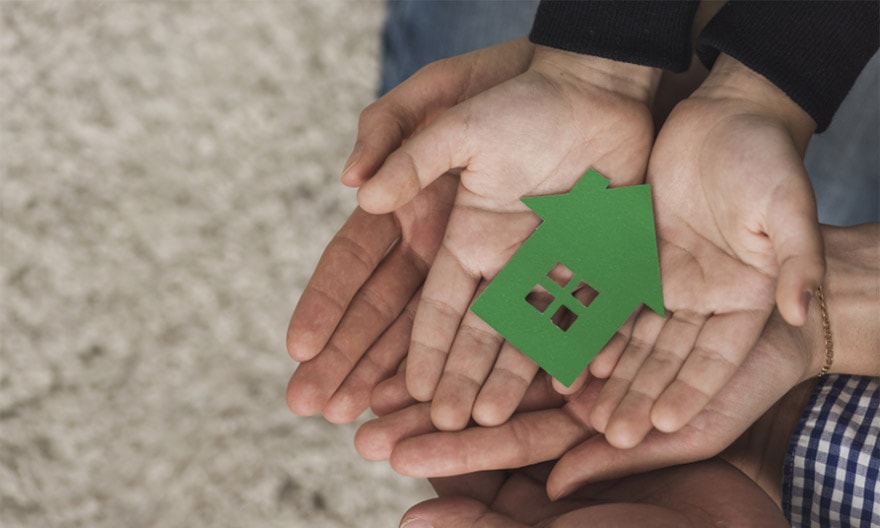 A father and son hold a green model of a house