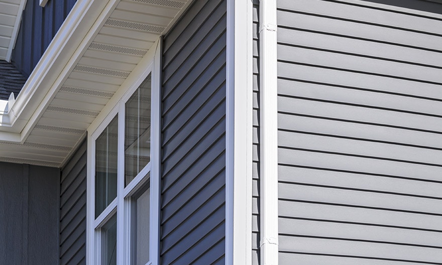 A view of gray siding on a house. Our siding contractors use high quality Royal and Mastic materials.
