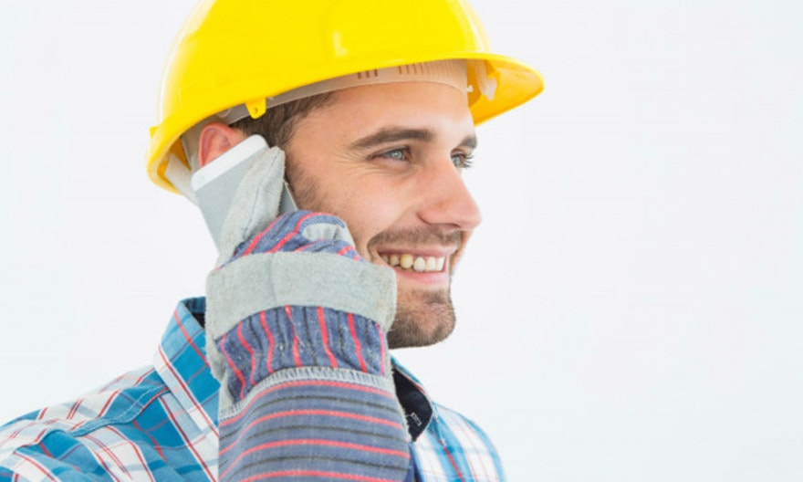 A contractor in a hard hat smiles as he talks on the phone with a customer